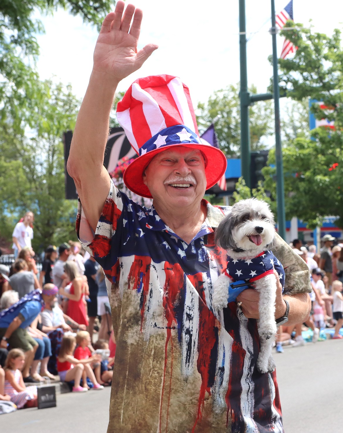 Gene Coryell waves to the crowd while holding his dog, Max, on Saturday.