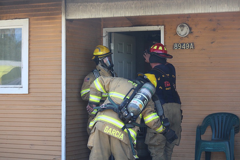 Grant County Fire District 5 firefighters prepare to enter a residence on Westover Boulevard north of Moses Lake Saturday morning to look for possible hot spots.