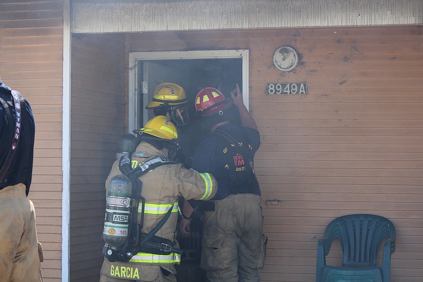 Grant County Fire District 5 firefighters prepare to enter a residence on Westover Boulevard north of Moses Lake Saturday morning to look for possible hot spots.