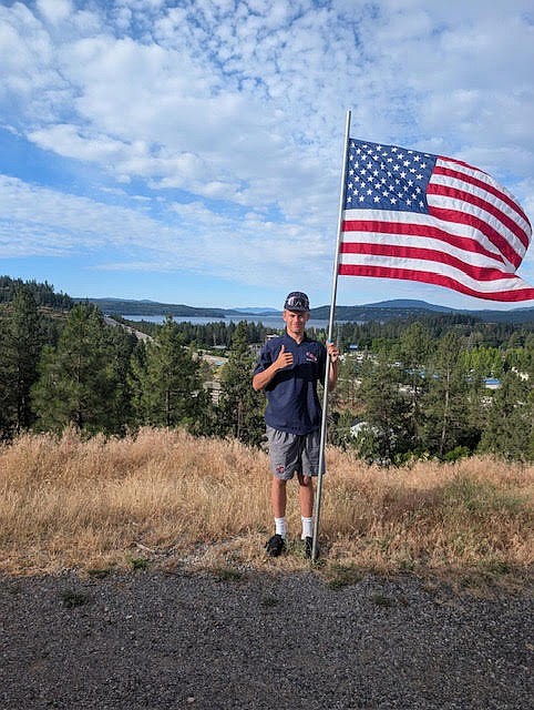 Courtesy photo
Aven Adams of the Coeur d'Alene Lumbermen AA team poses with a flag on the Fourth of July. The Coeur d'Alene Lumbermen AA team and 14U team partnered with the Kiwanis Club in lining the streets of Coeur d'Alene with American flags on the Fourth of July. More than 250 flags were placed along nine routes throughout the city; the Lums players returned that evening to pick them up.