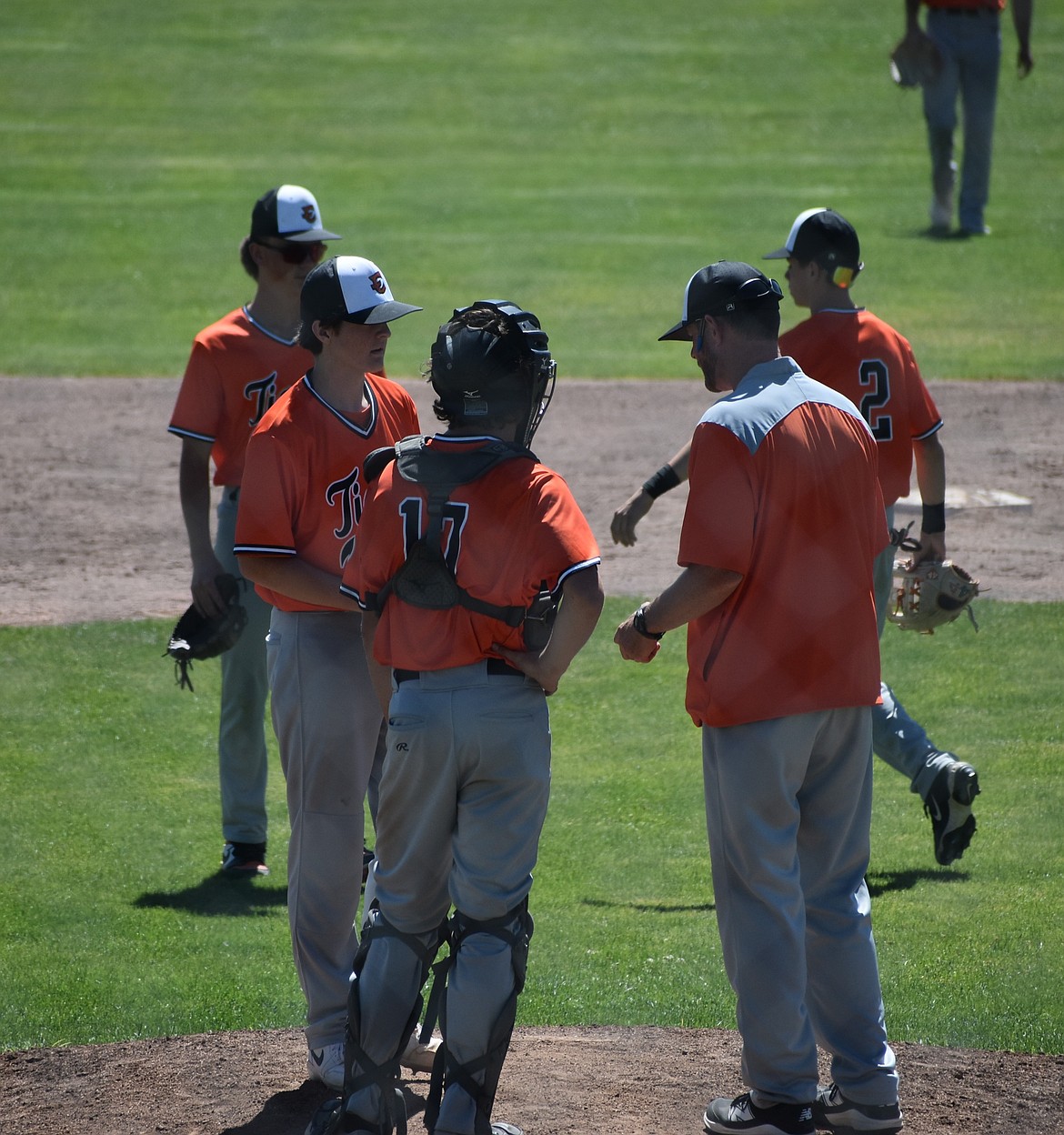 Tigers Head Coach David Tempel gathers his players on the mound to chat late in Thursday’s game against the Monarchs.