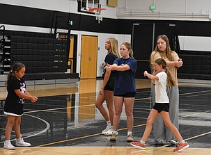 Royal high school players, Avery Scroggins, Anistynn Anderson and Michelle Woodward demonstrate proper hand placement for hitting the ball for some of the younger players during the summer camp.