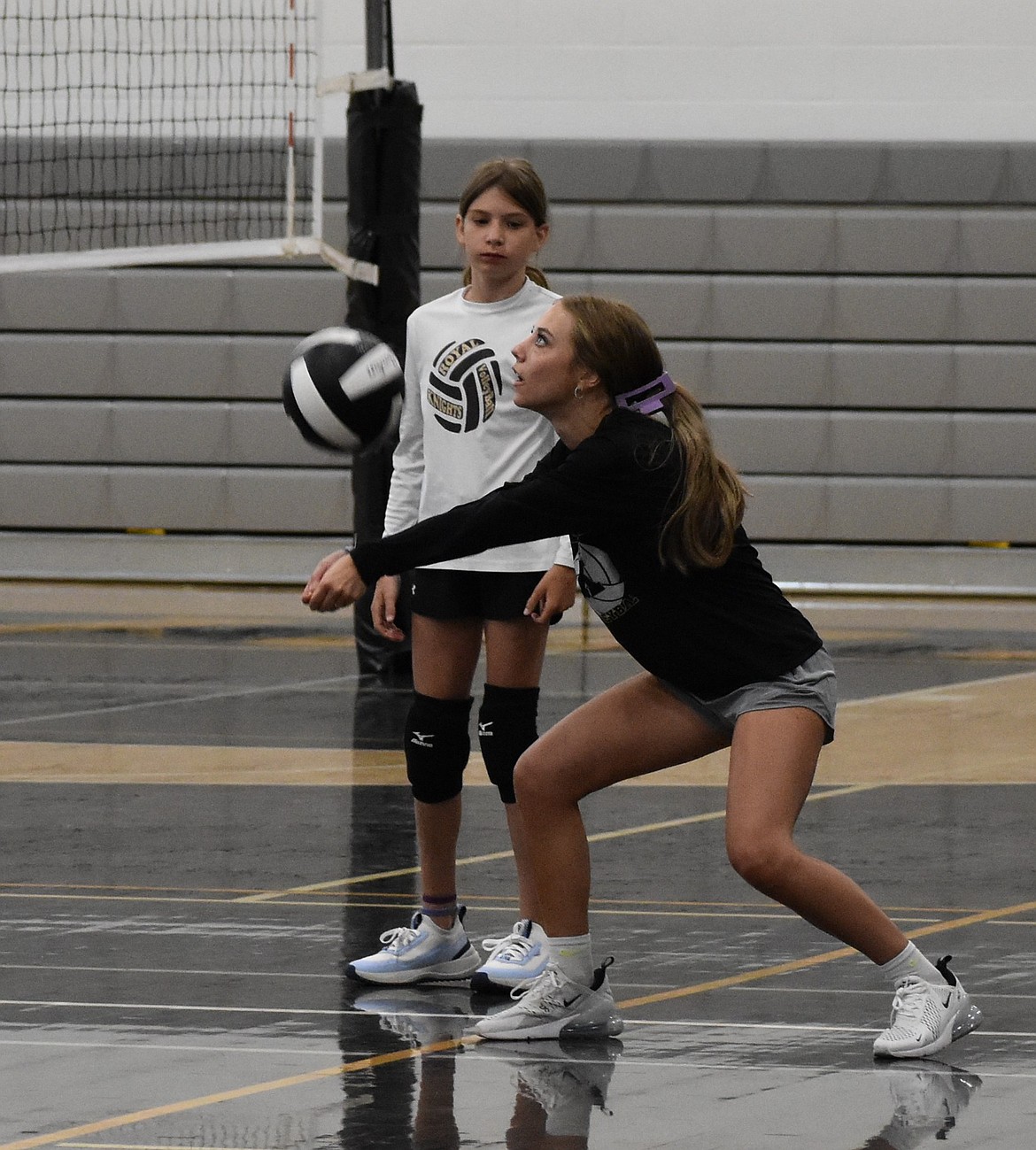Jaya Griffin demonstrates hitting the ball with Ashley Huntzinger keeping watch as the two act as coaches during the final day of the volleyball camp.