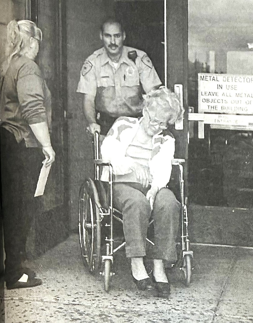Niece Jane Pittsley holds the door in 1996 while Rose Christmann, visibly shaken, is wheeled out of jail by Deputy Randy Smith.