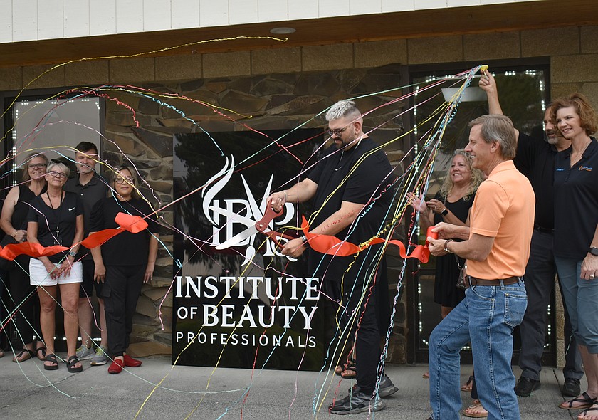 Institute of Beauty Professionals owner Nicholas Harle cuts the ribbon on his beauty school in Moses Lake, showered in streamers and surrounded by members of the Moses Lake Chamber of Commerce.