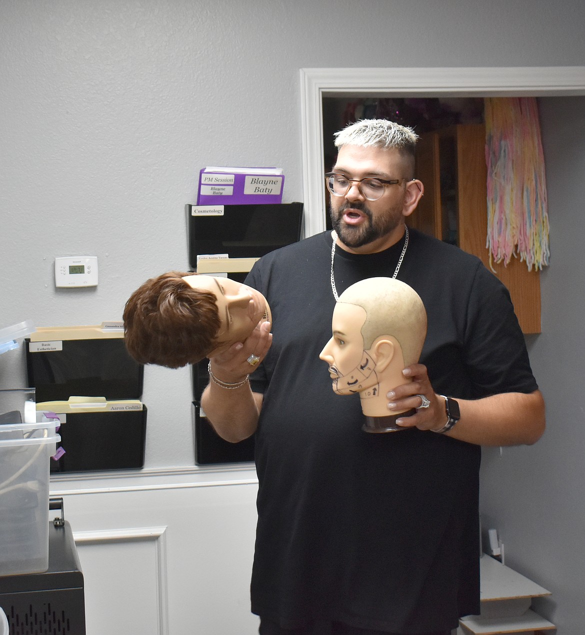 Institute of Beauty Professionals owner and instructor Nicholas Harle shows a couple of the practice heads IBP students use to learn proper hair-cutting and shaving techniques.