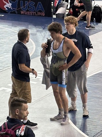 Conner Duvall (in singlet) talks with Eli Anderson (right) and their coach in between rounds of his match at the 2026 Fargo Nationals.