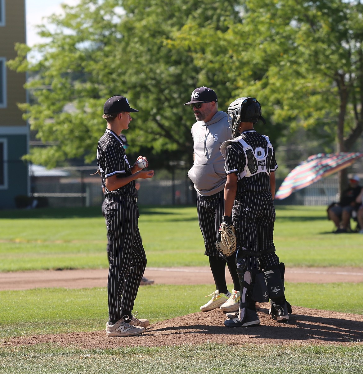 Sixers 14U Head Coach Steve Keller (gray hoodie) talks with pitcher Hesston Schwab (Left) and catcher Lukas Sawyer (8) on the mound during their championship game against the LC Outlaws, Sunday.