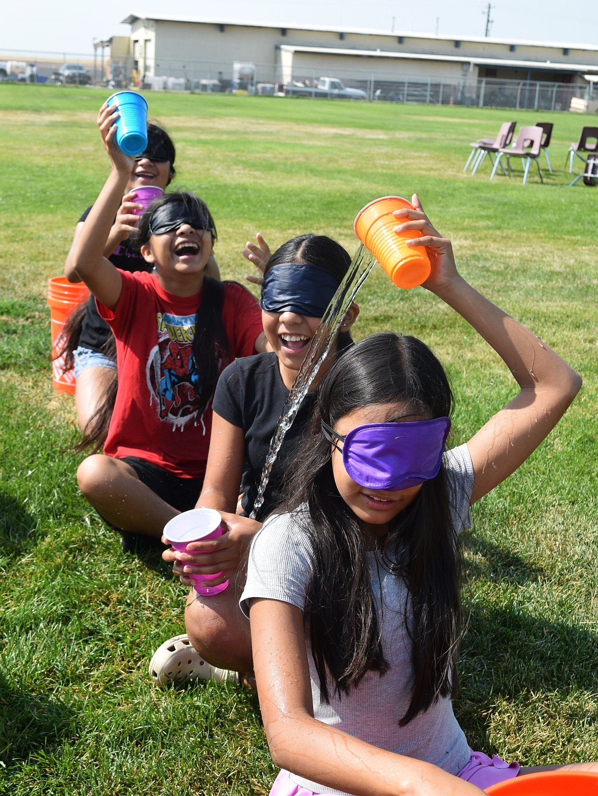 Warden Middle School students attempt to fill a bucket, blindfolded and racing against another team. Each student dumped the water they collected behind them, attempting to make it into the next cup.