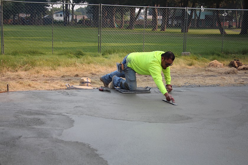 Ivan Orozco does the finish work on freshly poured concrete for the splash pad in Othello’s Kiwanis Park Tuesday.