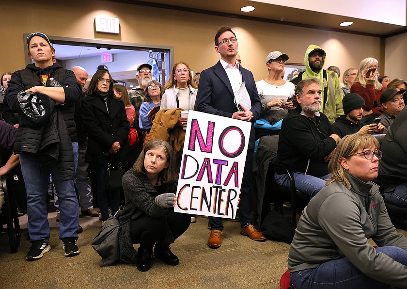 Jennifer-Ryan Barker holds up a sign expressing her opposition to a proposed data center being discussed during a special meeting of the Pacific Board of Aldermen at Pacific City Hall on Tuesday, Jan. 27, 2026. Also pictured is Keith Ketcherside, seated to the right with a beard, whose property abuts Crooked Creek Farm, the suggested site for a 500-acre data center near Pacific. (David Carson/St. Louis Post-Dispatch/TNS)