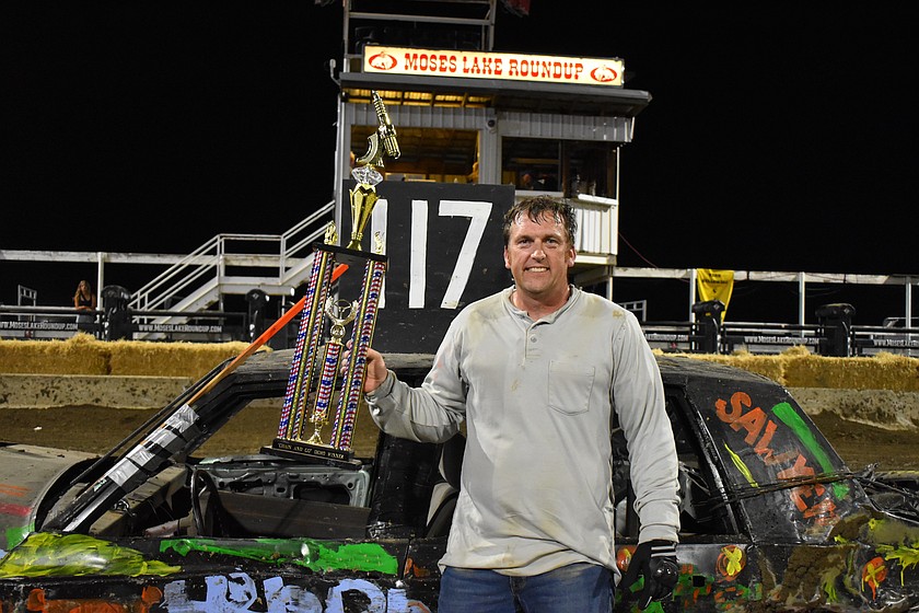 Michael Koon stands proudly with his trophy in hand next to his car after winning the demo event on the first day of the Moses Lake Roundup Demo Derby.