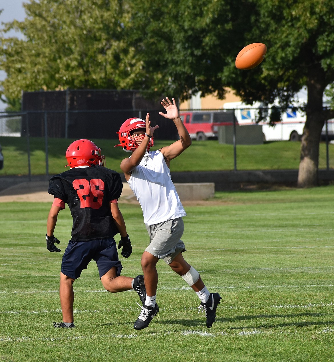 An Othello player looks to make a catch while his teammate defends during a hot summer practice.