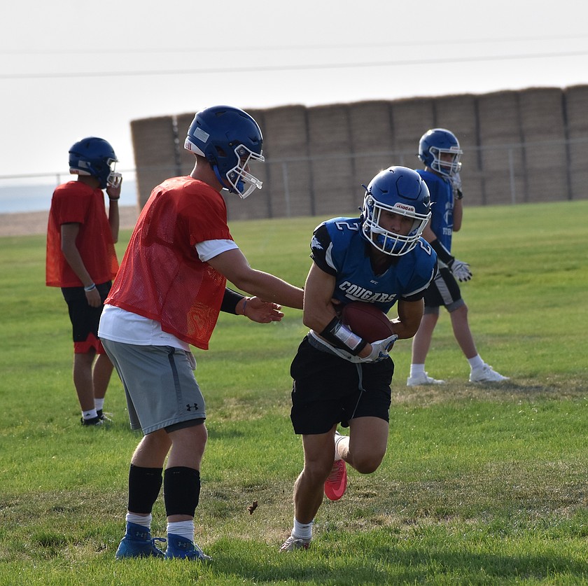 Kam Jensen, a senior from the Cougars, hands off the ball to Jaxsen Erickson during an early season practice.