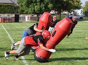 Othello players work on their defensive drills at practice as they slam into a tackle dummy.