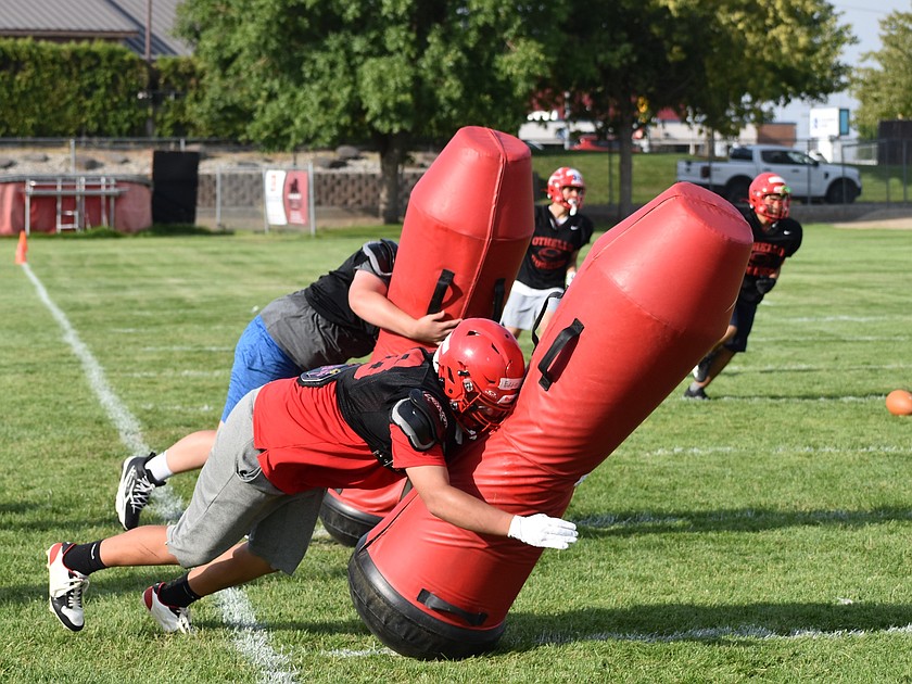 Othello players work on their defensive drills at practice as they slam into a tackle dummy.