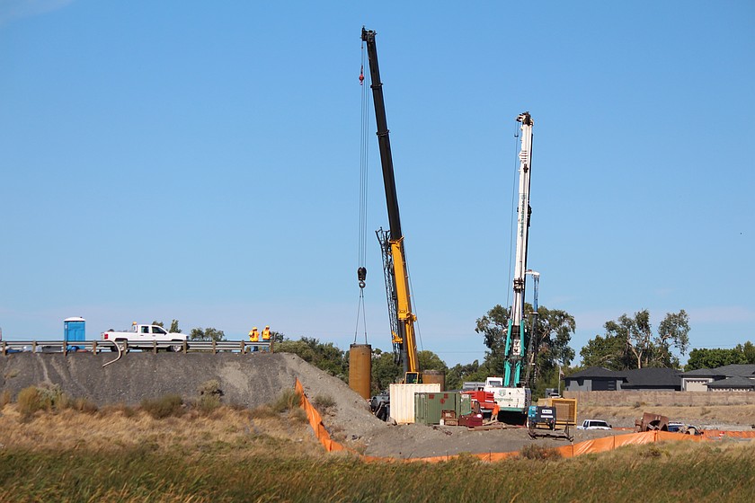 Construction crews work on support for the new Hansen Road overpass under the watchful eyes of a trio of inspectors.