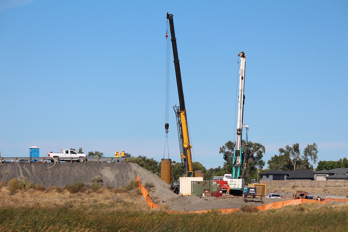 Construction crews work on support for the new Hansen Road overpass under the watchful eyes of a trio of inspectors.