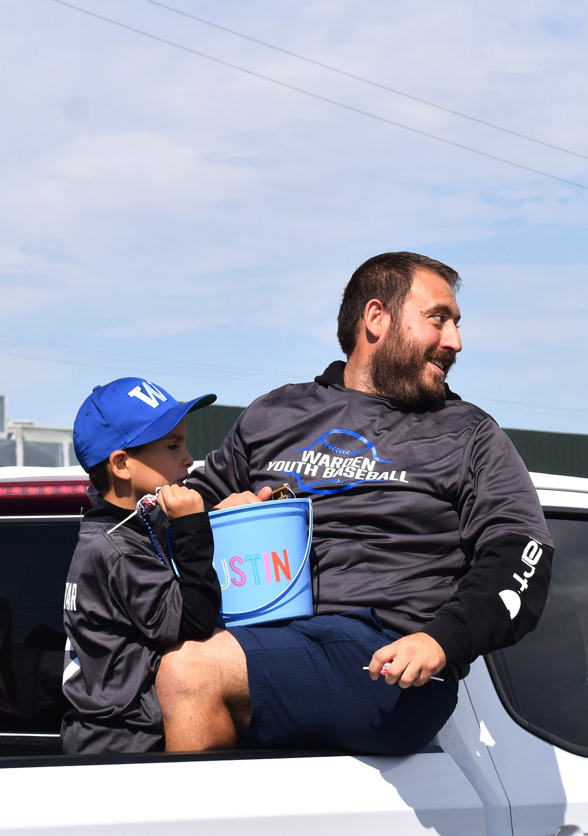 Warden City Councilmember Jesus Martinez and his son toss candy to spectators from the Warden Youth Baseball float during Monday's parade.
