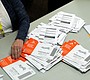 An election worker reaches for an unopened ballot …