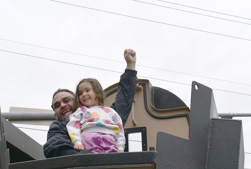 Three-year-old Vivian Garza and her dad Ricky Garza give a triumphant wave from the Moses Lake Tactical Response Team’s armored vehicle at National Night Out in Moses Lake Tuesday.