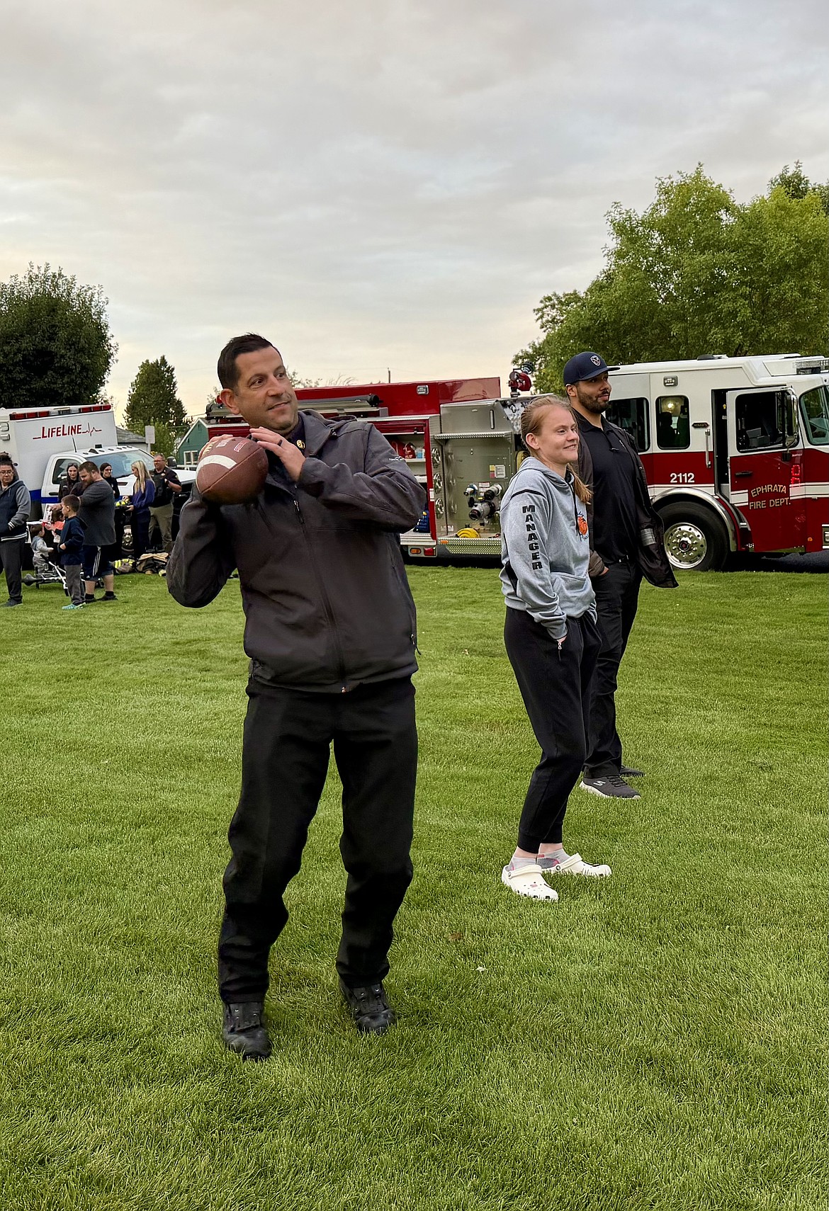 Ephrata Fire Chief Jeremy Burns throws a football with three young residents at National Night Out Tuesday at Lions Park.