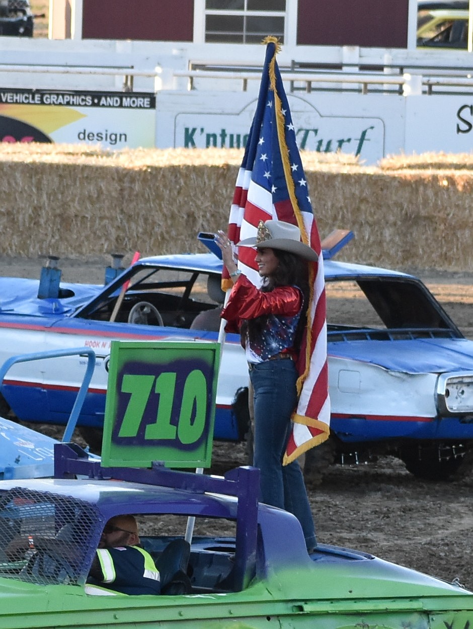 Miss Othello Rodeo Valeria Moreno stands atop one of the cars with the American flag in hand.
