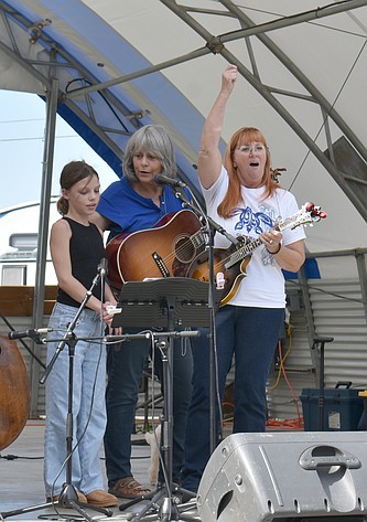 From left: George fourth-grader Everly Niderost joins Laurie Silcher and Monique Larsen on stage to sing “The Wellerman” at the George Bluegrass Festival Thursday.