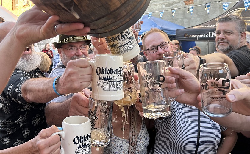 People hold out mugs to catch beer at the tapping of the keg as part of the Oktoberfest celebration in downtown Coeur d'Alene on Friday. Festivities continue from noon to 8 p.m. today with live music, German-inspired brews, and a tasting experience featuring more than 30 local craft beers, ciders, and Oktoberfest favorites. There will also be stein-holding competitions and a best-dressed contest showcasing traditional German attire.