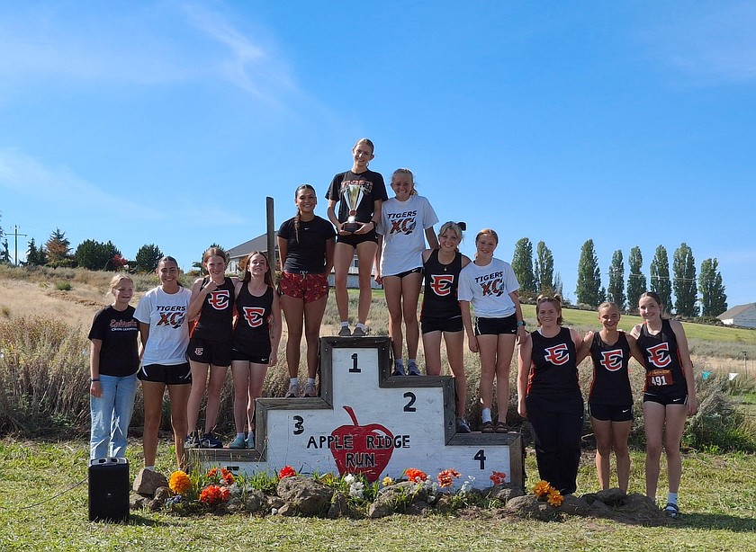 The Tigers girls cross country team stands together for a group photo as they hold up their first-place trophy after the Apple Ridge meet.