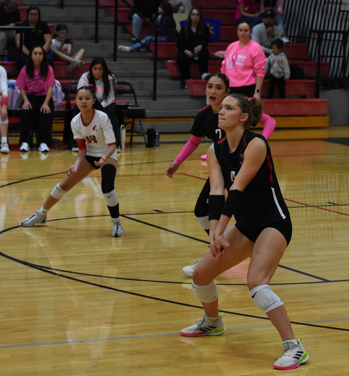 Huskies junior Julie Russell (4) prepares to hit the incoming serve with teammates Jena DeLeon (2) and Tekay Tran (14) keeping watch on the play.