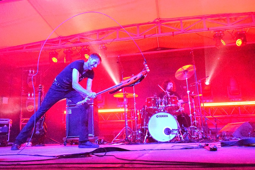 Travis Wolfe, bassist for Nevermind, caps off the band's Friday night performance at Flannel Fest by smashing his bass guitar, recreating the raw energy and stage antics that helped define the grunge era.