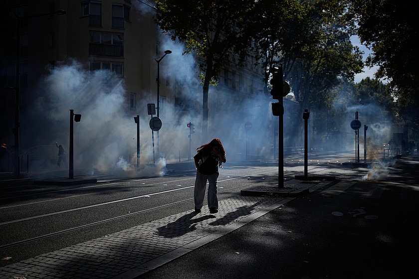 A student runs out the teargas during a protest against under-resourced schools in Lyon, France, Friday, Oct. 2, 2026. (AP Photo/Laurent Cipriani)