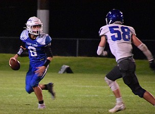Soap Lake’s quarterback Tyler Hart eyes the oncoming Manson defender as he looks for an opening to pass or run with the ball himself Friday night.