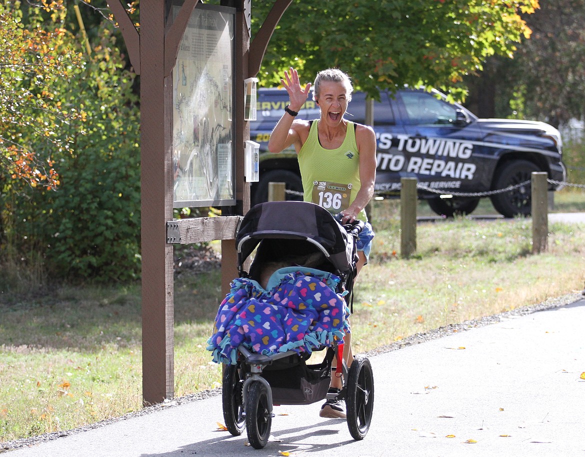 Ashten Berti, who recently qualified for the Boston Marathon, smiles and waves during the Jackass Half Marathon last Saturday in the Silver Valley.