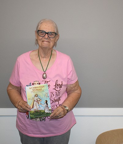 Chaplain Linda Curran holds her self-published book “A Christian Woman Striving to Live Her Faith in a Man-Controlled World,” available on Amazon.
