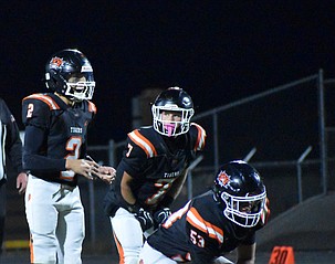 Tigers running back Chance Lee (7) watches quarterback Cooper Vasquez (2) as he prepares to call for the snap and offensive guard Trenton Taylor (53) in position to block for them.