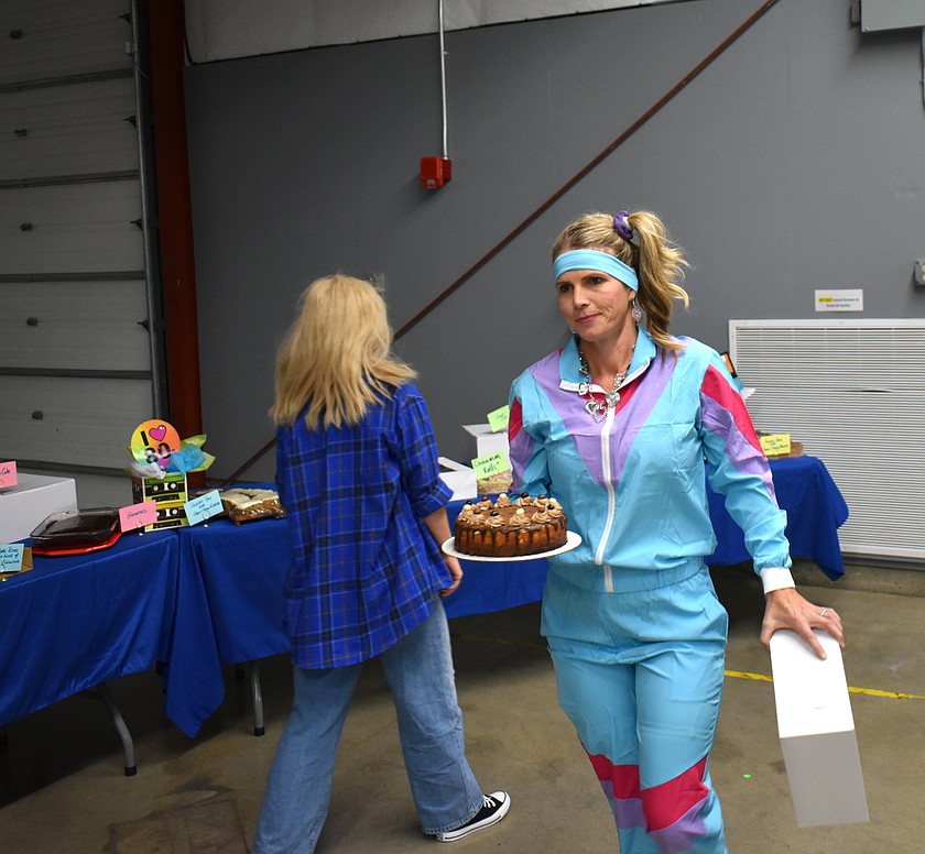 Caitlin Graves, dressed in '80s regalia, heads to her table with a dessert from the dessert dash at the Youth Dynamics auction Saturday.