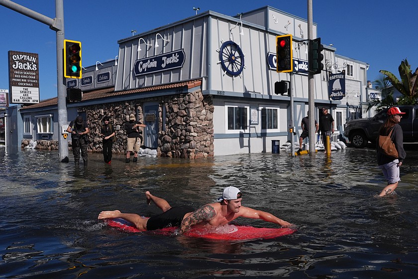 A man surfs through floodwaters in Huntington Beach, Calif., Wednesday, Oct. 28, 2026. (AP Photo/Jae C. Hong)