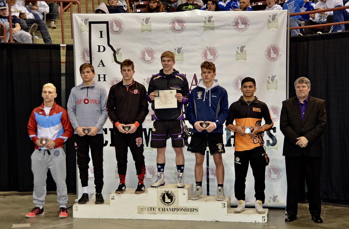 Kellogg’s Judson Hall stands at the top of the podium after winning the 138-pound championship at the 3A State Wrestling Championships in Nampa. Kellogg head coach Scott Miller is standing on the far right.